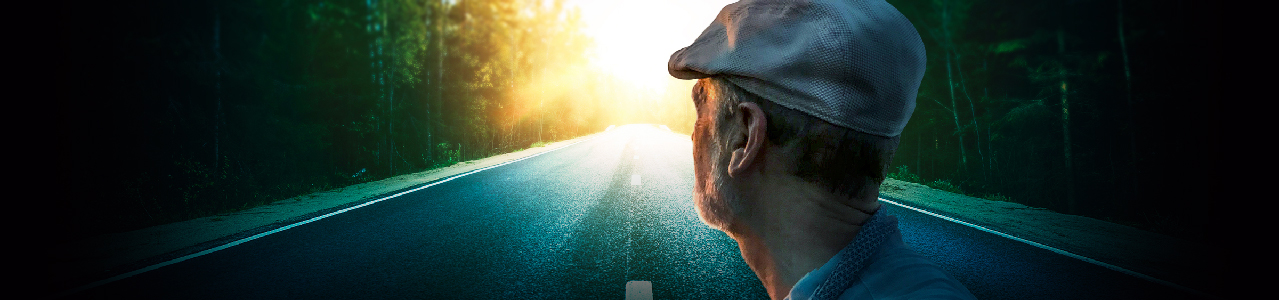 Image of older man gazing down a road toward the sunset